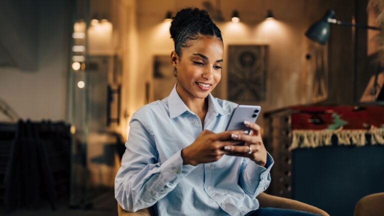 Smiling African woman using a mobile phone at the home office.