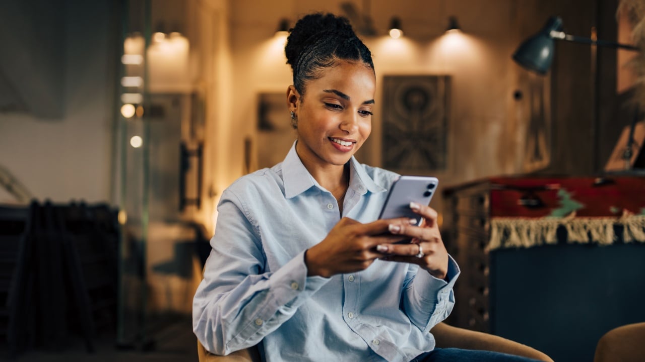 Smiling African woman using a mobile phone at the home office.
