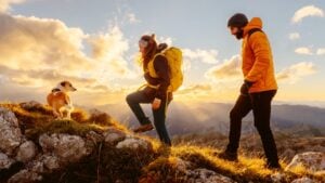 couple of two mountaineers with their adopted dog on a mountain route at sunset. Traveling and playing sports with pets. outdoor activities and adventure.