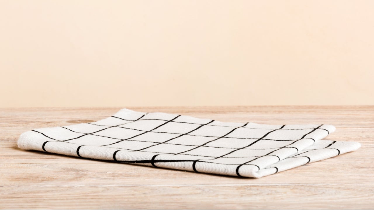 top view with white empty kitchen napkin isolated on table background. Folded cloth for mockup with copy space, Flat lay. Minimal style.