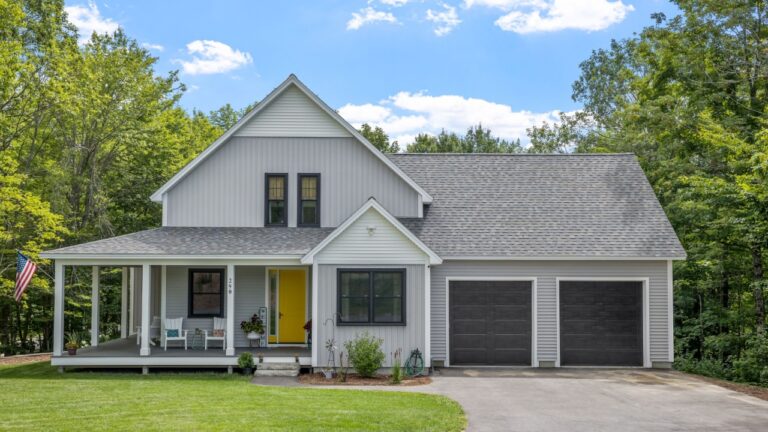 A modern custom new England colonial home with an American flag on a sunny day