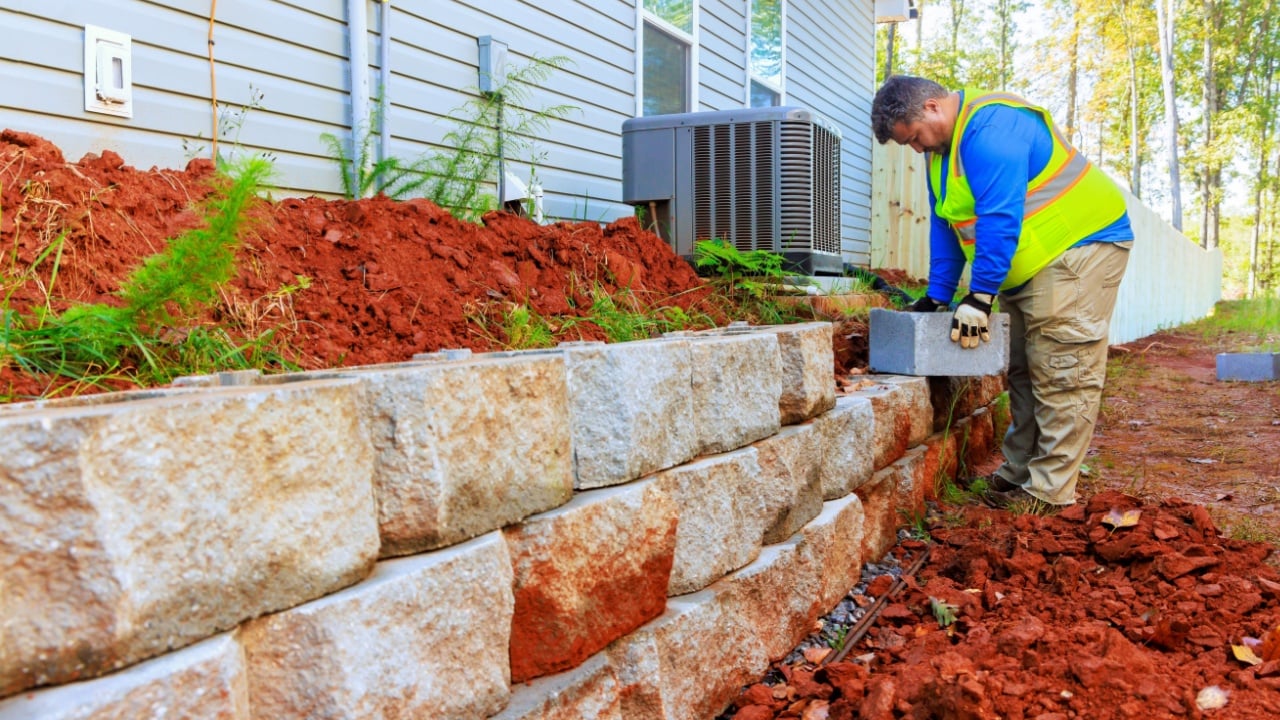 Concrete blocks are mounted to retaining wall by construction worker