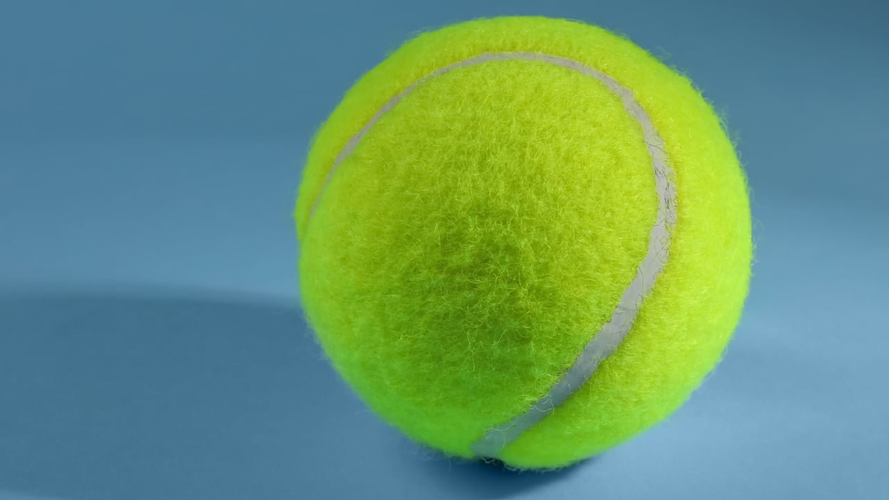 One tennis ball on light blue background,