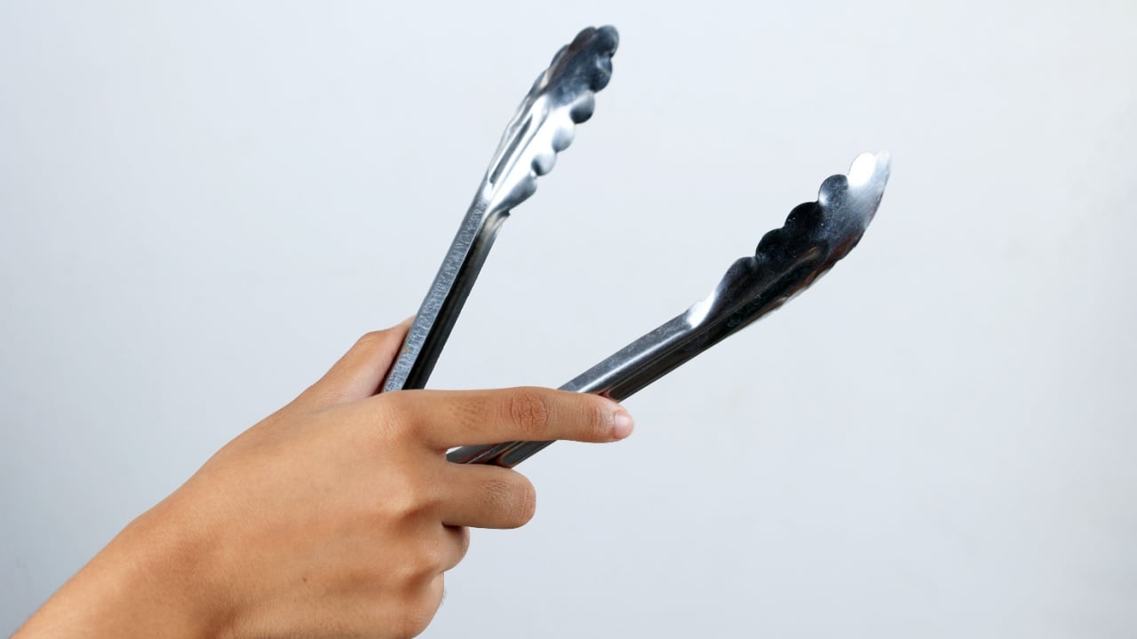 Female Hand Hold Stainless Tongs for Serving Picking Food, Isolated on White