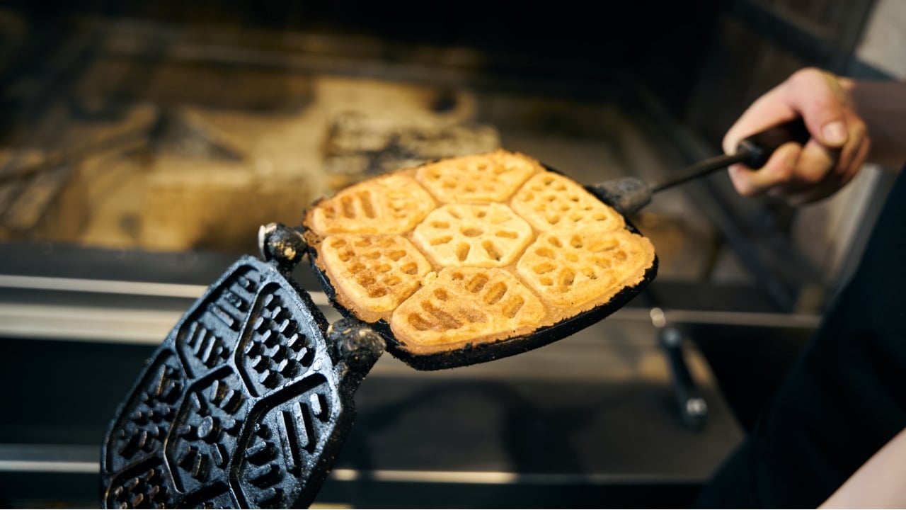 Cropped male chef holding frying pancake in pancake maker in restaurant