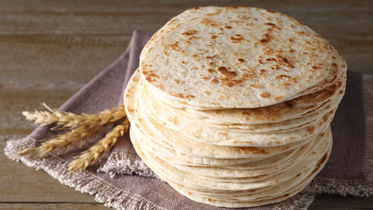 Many tasty homemade tortillas on wooden table, closeup