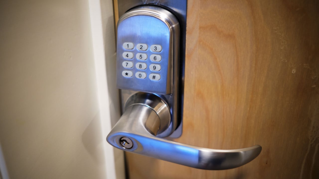 A close-up of a modern electronic door lock with a keypad and lever handle, installed on wooden door