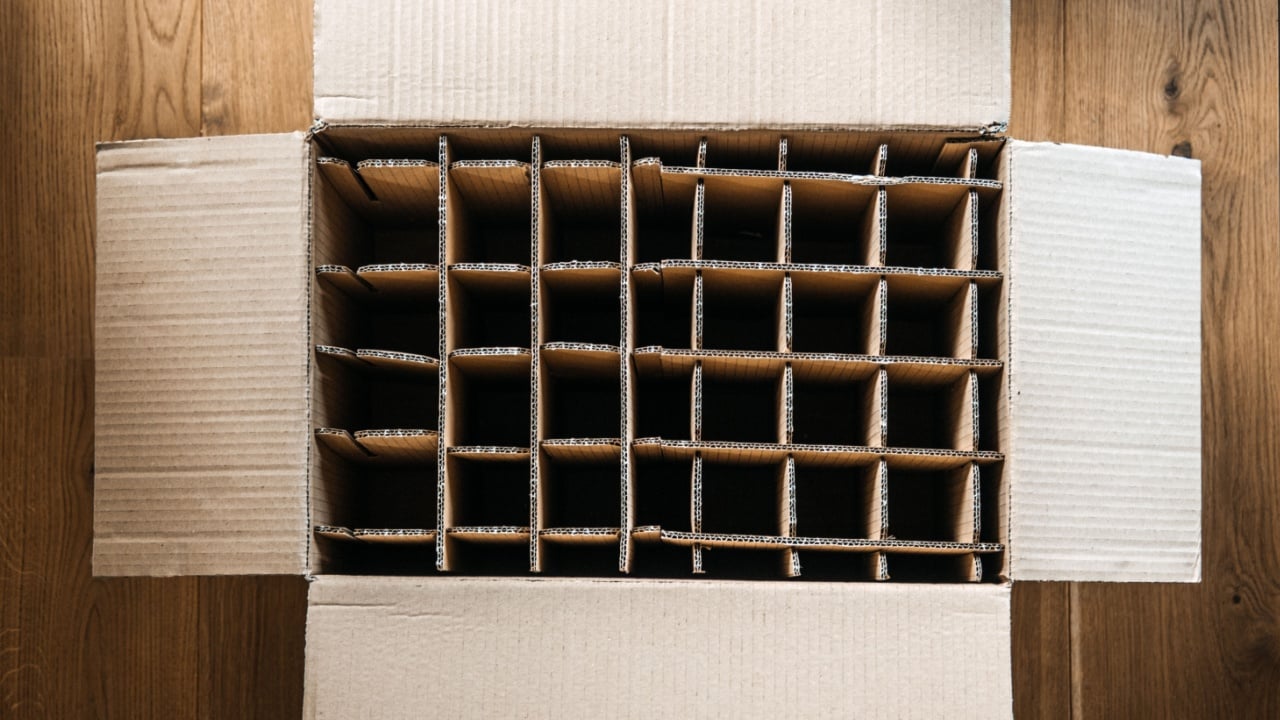 Corrugated cardboard wine bottle packaging with empty slots. Sustainable packaging, beverage logistics, wine shipping protection, eco-friendly packaging solutions.