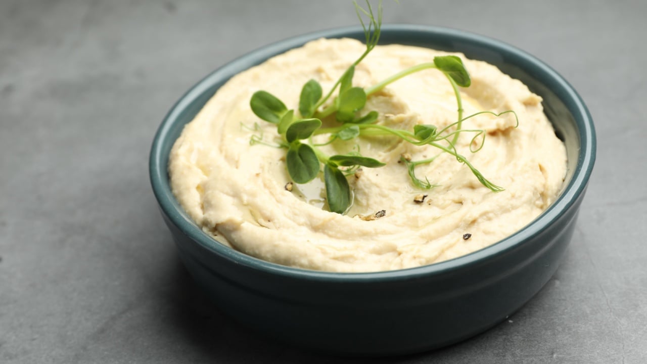 Delicious hummus in bowl on grey table, closeup