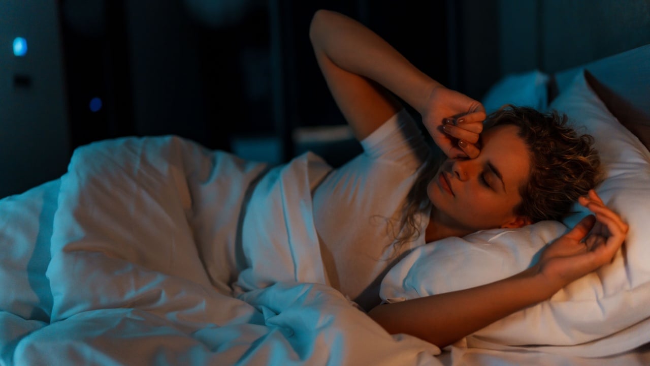 Woman waking up and rubbing her eyes in bed.