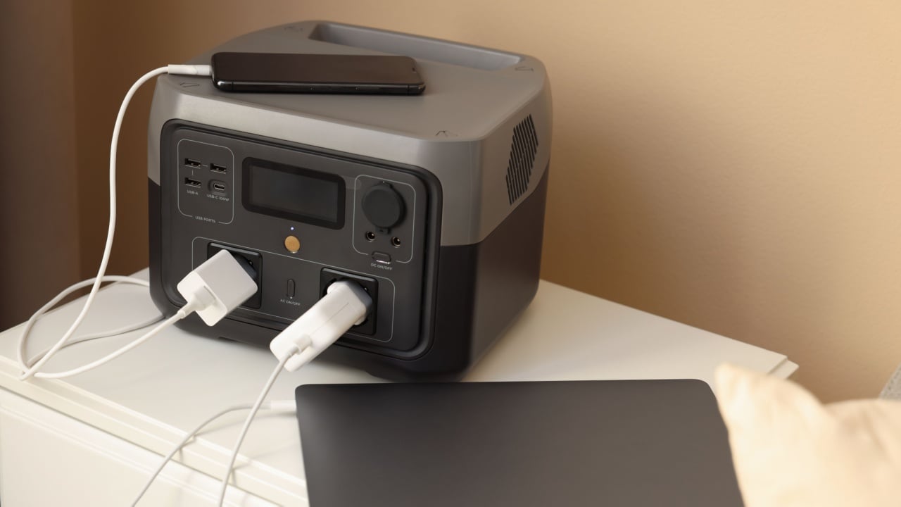 Devices charging from portable power station on nightstand indoors