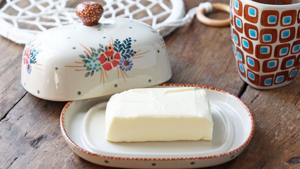 Beautiful ceramic butter dish with butter briquettes on the kitchen table. Selective focus.