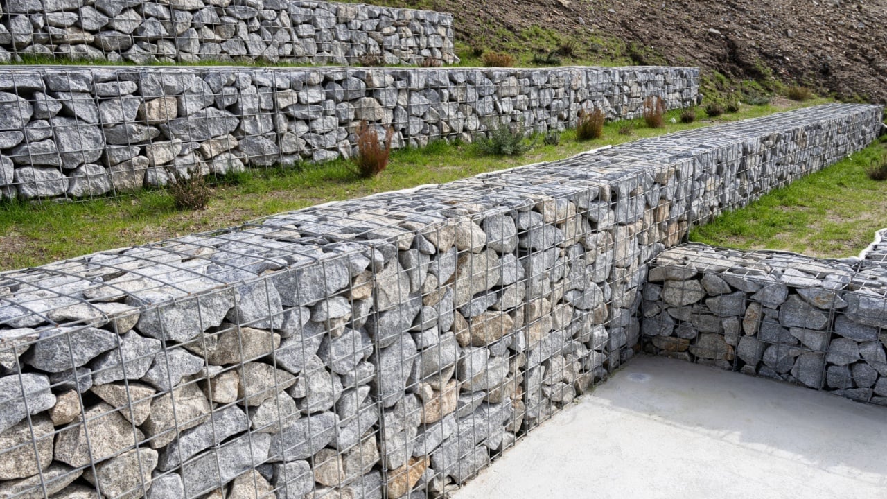 Modern gabion walls made of granite stones and wire mesh, used for landscaping on a public park