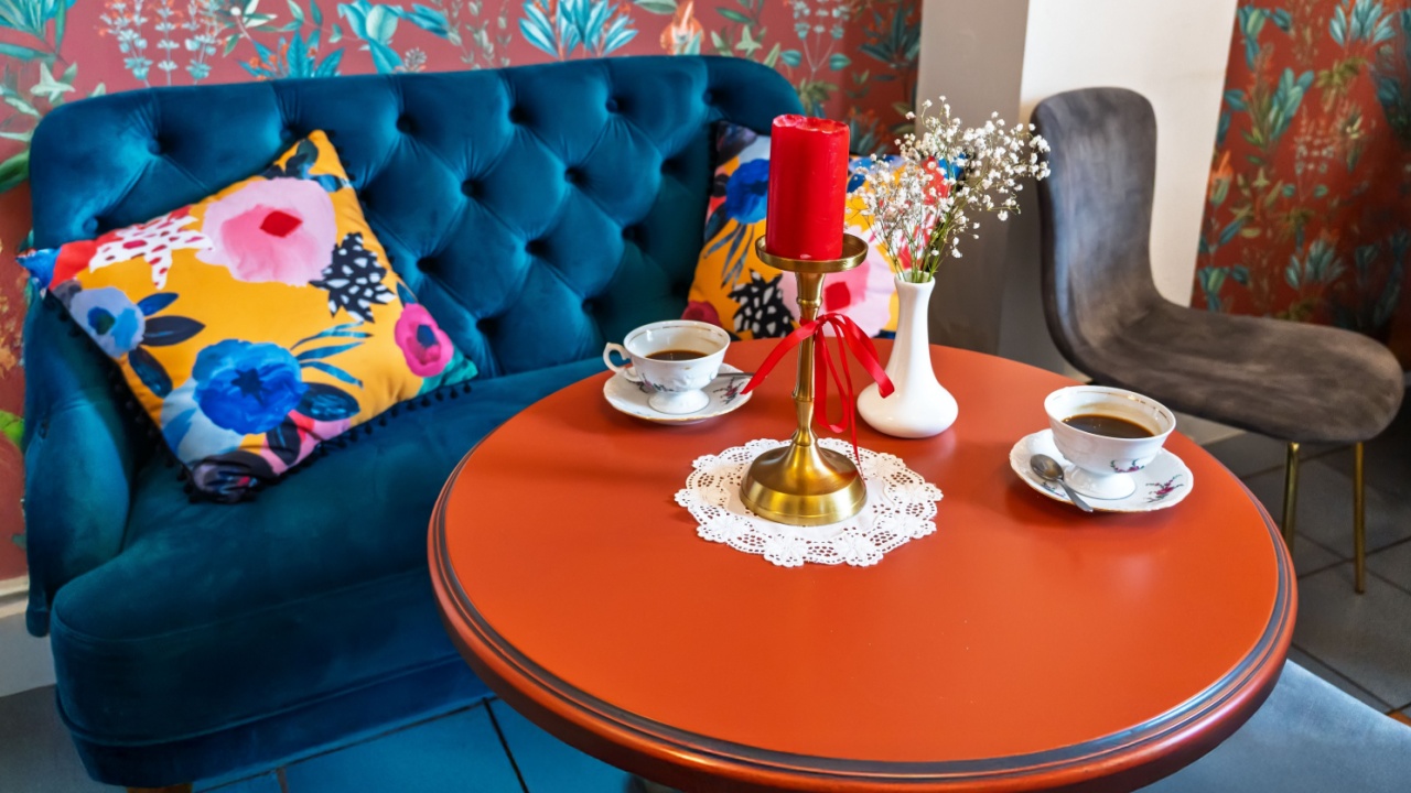 Vibrant Cafe Corner with Blue Velvet Sofa and Orange Table.Cozy Coffee Setting with Floral Wallpaper and Navy Tufted Loveseat.