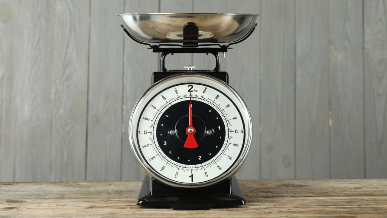 Mechanical kitchen scale with bowl on wooden table