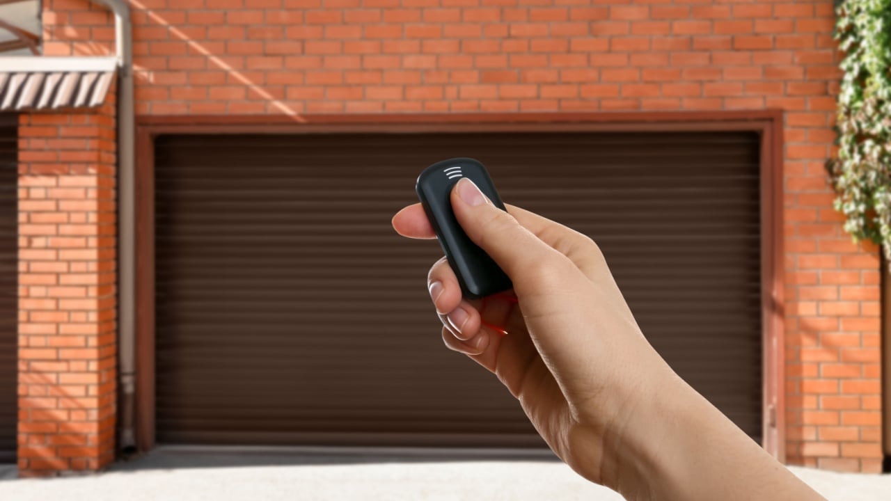 Woman using remote to control garage door outdoors, closeup