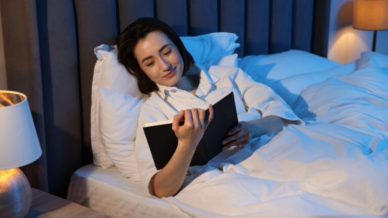 Young woman reading book in bed at home