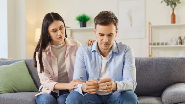 Married couple engages in conversation at home, with wife offering support to sad husband, addressing depression and nurturing family relationship through open communication in a domestic comfort.