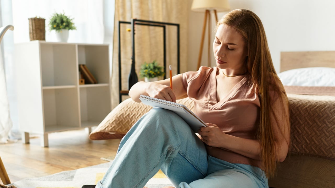 Young woman enjoys a creative moment at home, sketching thoughtfully on a cozy floor rug.