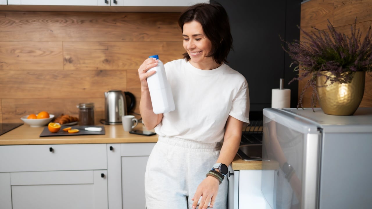 Joyful Woman On The Kitchen Grabbing Milk Bottle From Fridge