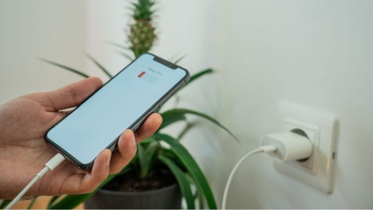 Close-up of a smartphone connected to a wall socket with a USB cable for charging. Modern technology and home electricity concept.