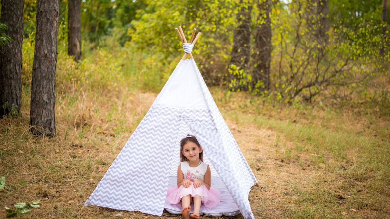 Teepee, child and fun in garden tent outdoor in nature for camping, playing and adventure with sunlight. Cloth, lamp and fantasy house for girl in forest with imagination. eco toys
