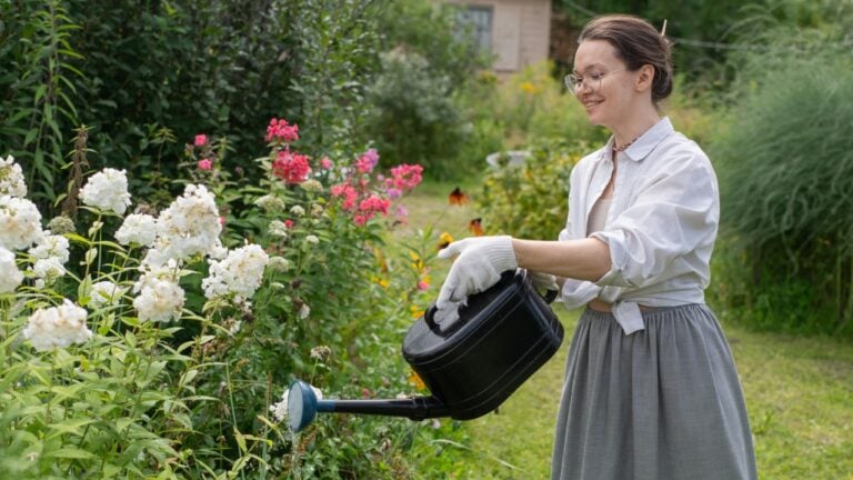 Young Caucasian woman watering flowers in the garden.