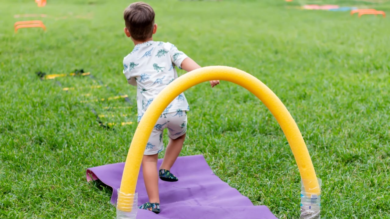 The boy overcomes an obstacle course. The child is playing on the green grass. Sport and recreation concept.