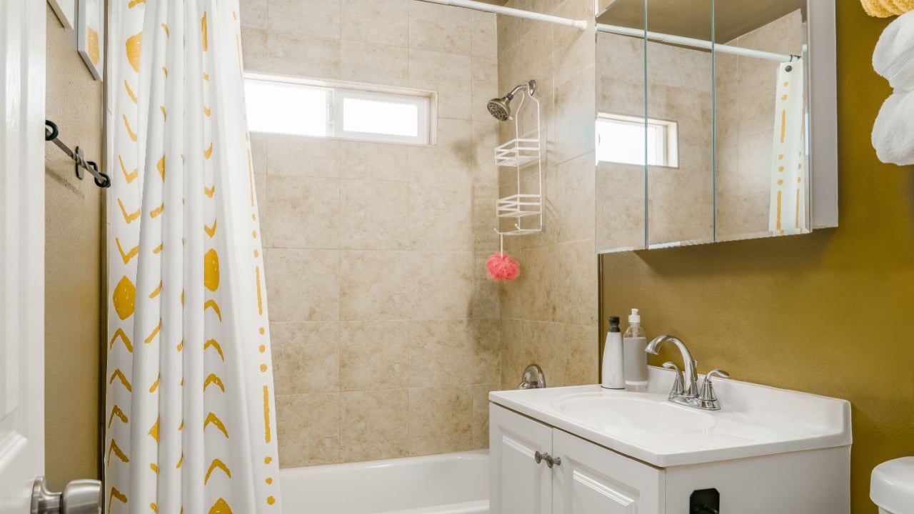 Bathroom interior in modern yellow color with shower, sink, and mirror