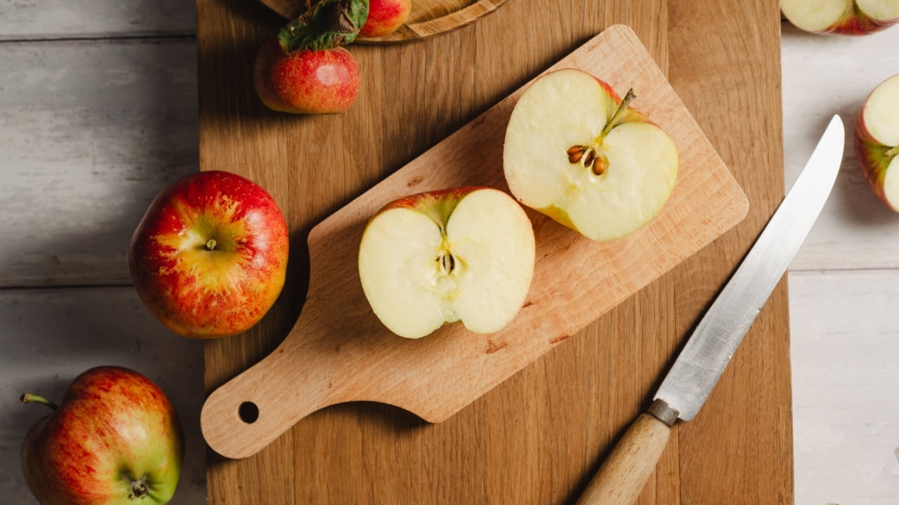 Red apples, whole and sliced on a wooden cutting board, lifestyle, top view. Autumn abstract food background