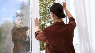 Woman opening modern window at home, back view