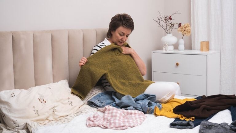 Woman selecting clothes from her wardrobe for donating to a Charity shop. Decluttering, Sorting clothes and Cleaning Up. Reuse, second-hand concept. Conscious consumer.