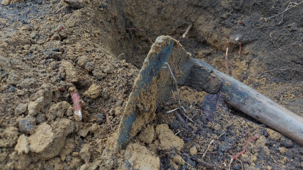 The hoe blade full of soil lay at the edge of the excavation