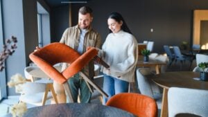 Couple smiling, examining and choosing new modern upholstered chairs for their home in a contemporary furniture showroom
