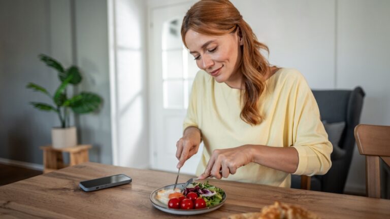 Happy woman enjoying healthy and nutritious breakfast with salad, cherry tomatoes, and fried egg at home, focusing on wellness and domestic life in the morning