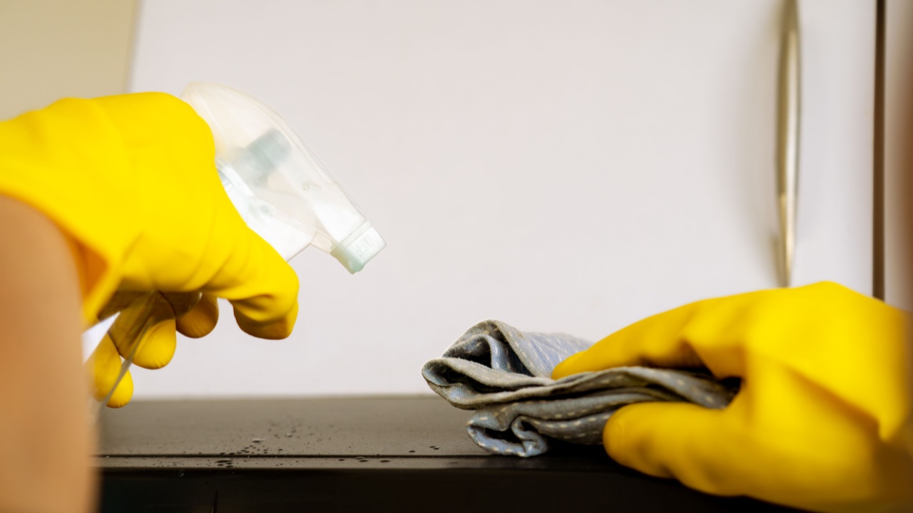 Professional male cleaner sanitizing modern kitchen, wiping countertops and appliances to maintain a hygienic and safe cooking environment.