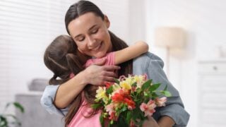 Happy Mother's Day. Little girl greeting her mom with beautiful flowers indoors