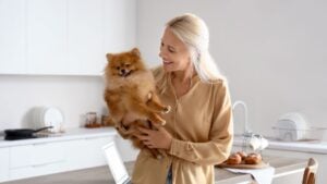 Mature woman with Pomeranian dog in kitchen