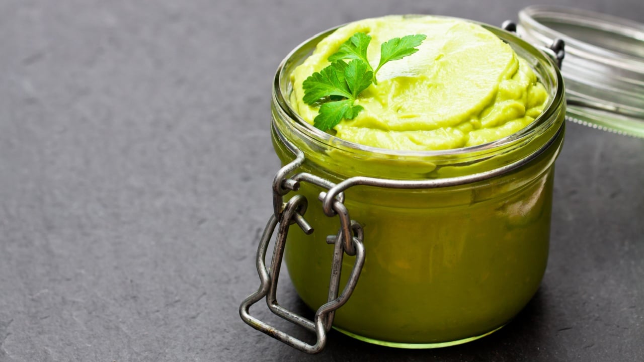 Mexican sauce guacamole in a jar on black stone background 