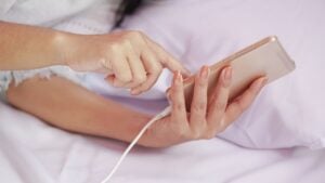 Asian woman hand using charging smart phone on bed , people and technology concept