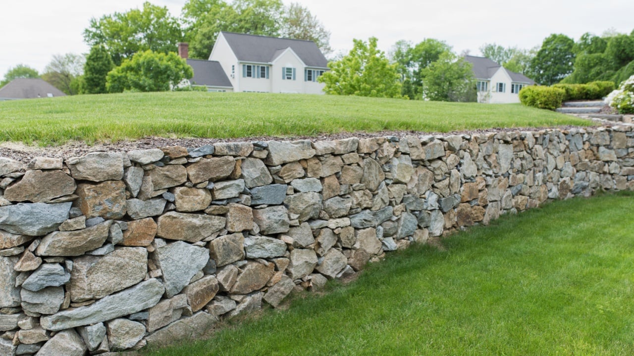 Large rock wall used in landscaping design for residential neighborhood. Stone wall background texture