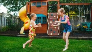 Portrait of two little girls sisters fighting on home backyard. Friends girls having fun. Lifestyle candid family moment of siblings quarreling playing together.