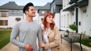 Smiling couple walking at residential area near their new home.
