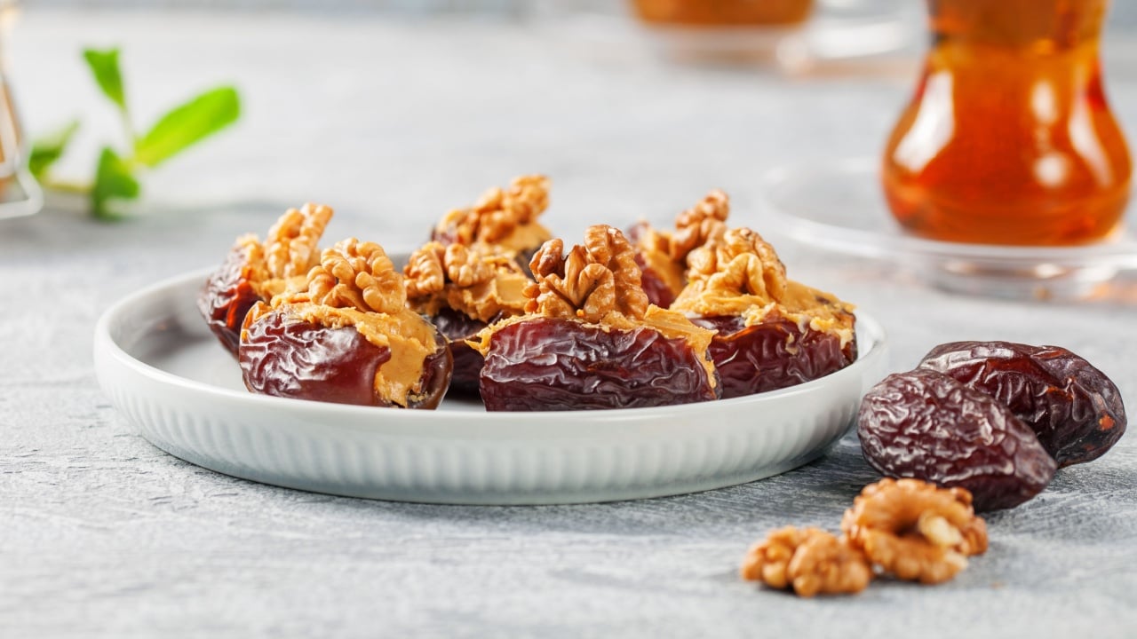 Dates Medjool stuffed with nut cream cheese and walnuts on grey background.