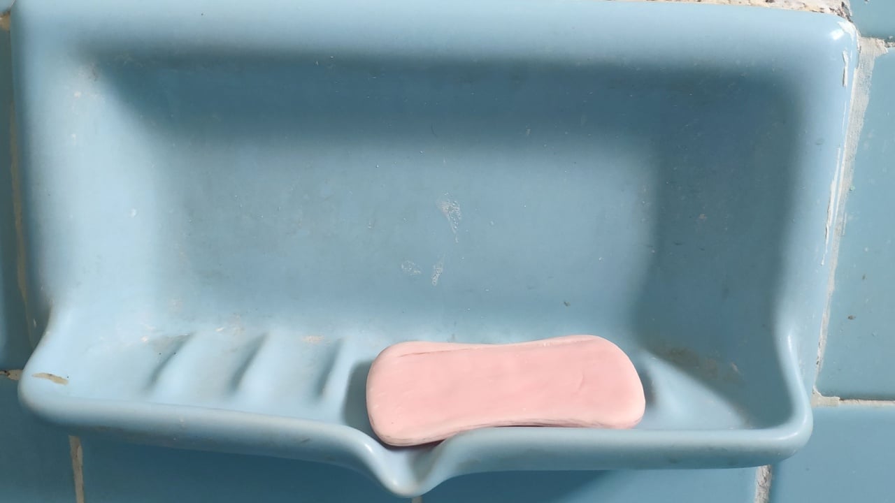 Pink soap that is used and placed on the blue place in the bathroom.