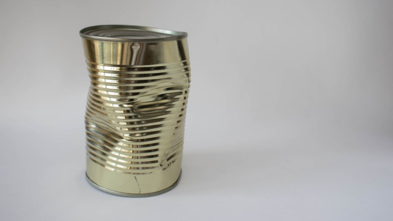 Dented tin can on a white background
