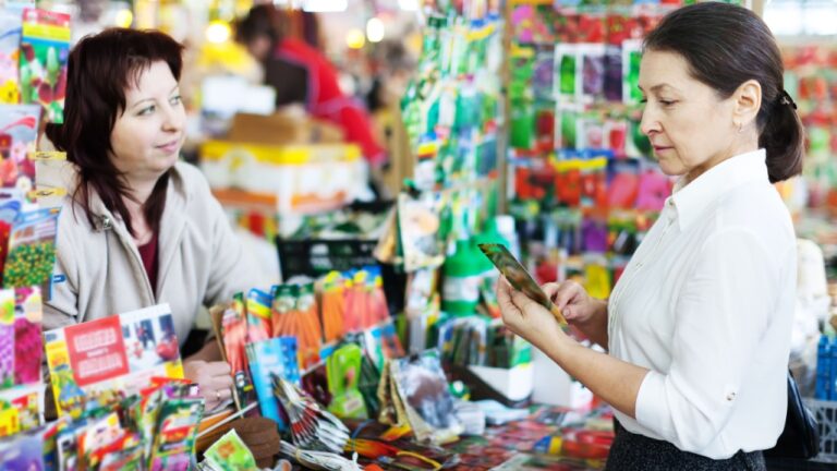 mature woman chooses packed seeds at store for gardener