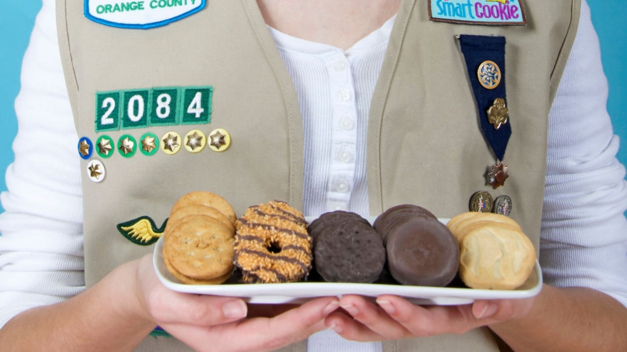 Alameda, CA - Feb 18, 2016: Cadette Girl Scout wearing uniform vest holding a white rectangular plate with the five most popular original Girl Scout cookies created by ABC Bakers.