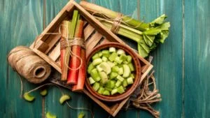Rhubarb stalks on a board, Rhubarb in bowl on a wooden background. Rhubarb stalks on a board, Rhubarb in bowl on a wooden background. top view.