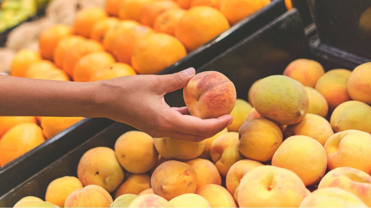 Young girl Choosing Peach at a grocery store. Concept of healthy food, bio, vegetarian, diet.